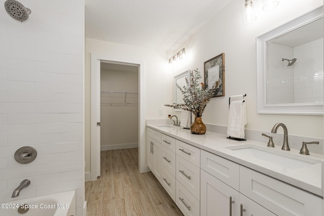 bathroom with tiled shower / bath, vanity, hardwood / wood-style floors, and a textured ceiling