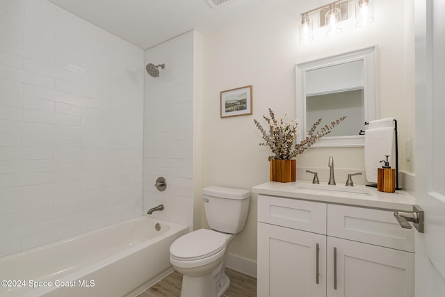 full bathroom with tiled shower / bath, vanity, hardwood / wood-style floors, and toilet