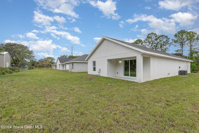 rear view of house featuring a yard and central AC unit