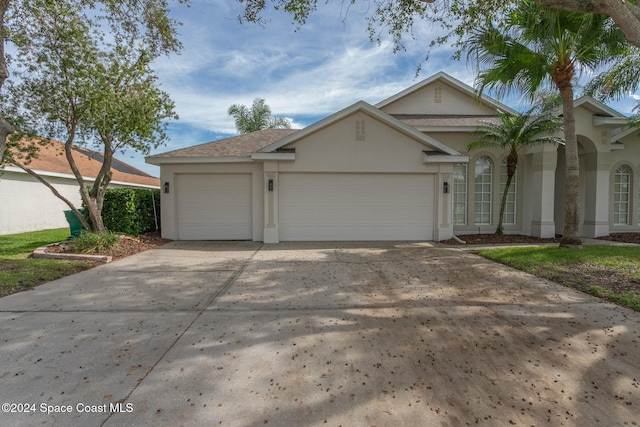 single story home with roof with shingles, driveway, an attached garage, and stucco siding