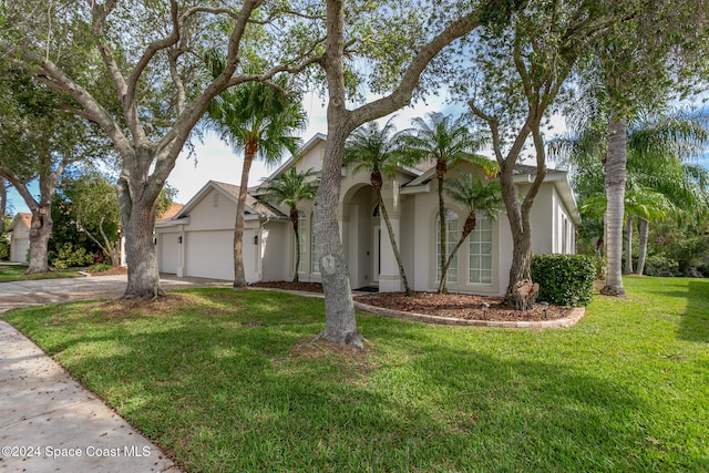 view of front of home featuring a garage, a front yard, driveway, and stucco siding