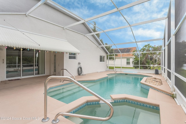 outdoor pool featuring glass enclosure, a patio, and an in ground hot tub