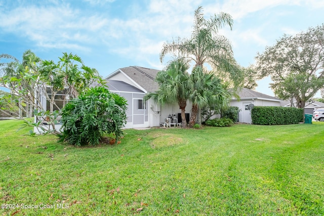 rear view of house featuring a lanai, a lawn, and stucco siding