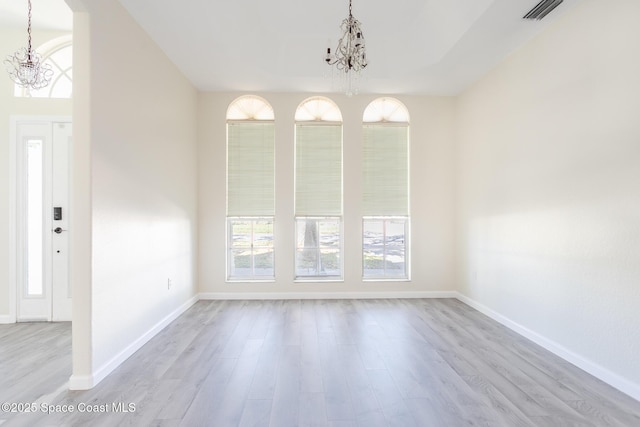 unfurnished dining area with a chandelier, wood finished floors, visible vents, and baseboards