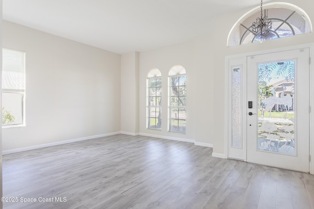 entrance foyer with light wood-type flooring, baseboards, and a notable chandelier