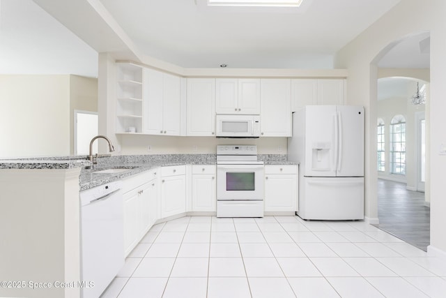 kitchen featuring arched walkways, open shelves, light tile patterned flooring, a sink, and white appliances