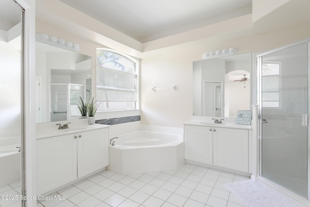 bathroom featuring a bath, a shower stall, two vanities, and a sink