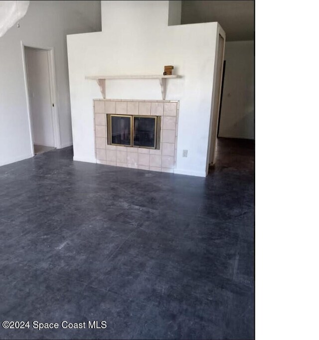 unfurnished living room with a fireplace and a towering ceiling