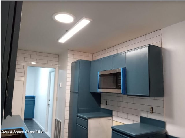 kitchen featuring blue cabinetry and tile walls