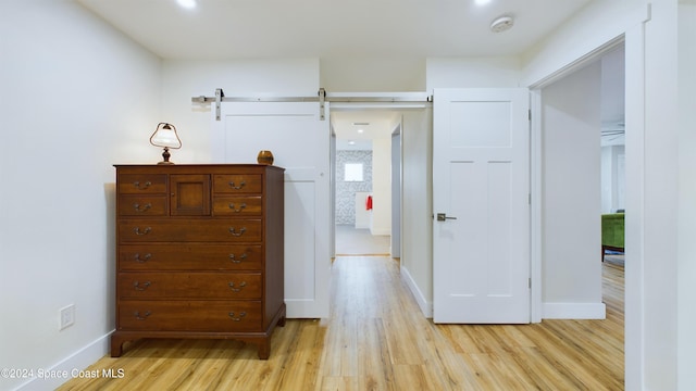 bedroom with light hardwood / wood-style flooring and a barn door