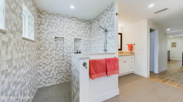 bathroom featuring wood-type flooring, vanity, and tiled shower