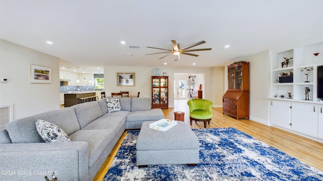 living room with light hardwood / wood-style flooring and ceiling fan