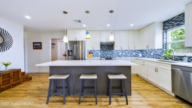 kitchen with stainless steel appliances, hanging light fixtures, light wood-type flooring, and a center island