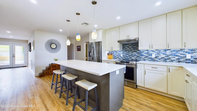 kitchen featuring stainless steel appliances, hanging light fixtures, light hardwood / wood-style flooring, a kitchen island, and white cabinets