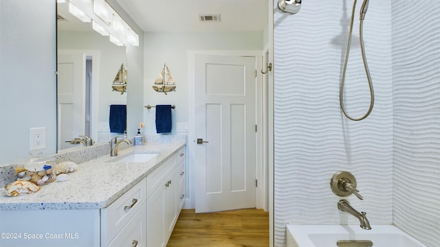 bathroom with washtub / shower combination, vanity, and hardwood / wood-style flooring