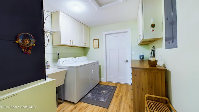 laundry room featuring cabinets, light hardwood / wood-style floors, electric panel, and washer and clothes dryer