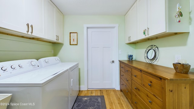 laundry area featuring cabinets, separate washer and dryer, and light hardwood / wood-style flooring