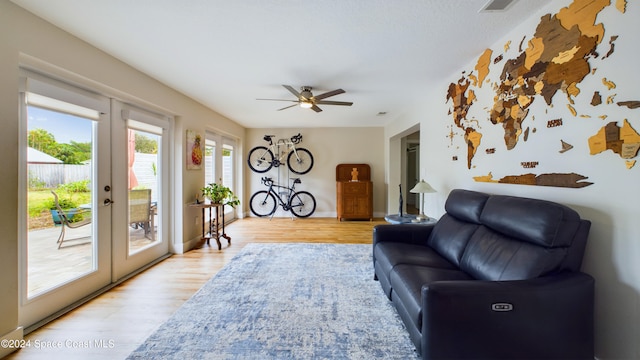 living room with light hardwood / wood-style floors, ceiling fan, and french doors