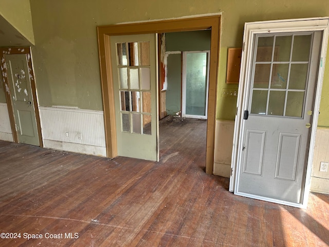 empty room with hardwood / wood-style floors and wainscoting