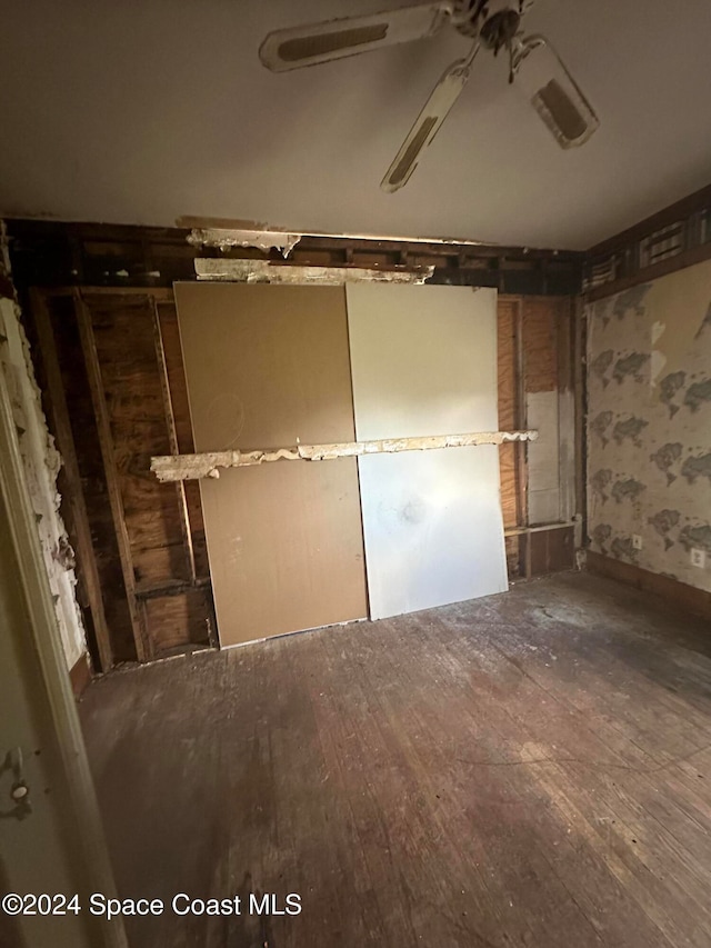 unfurnished bedroom featuring wallpapered walls, a ceiling fan, and wood finished floors