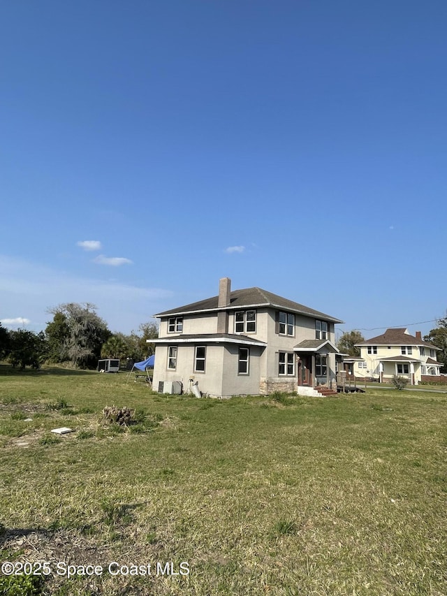 back of property featuring stucco siding and a yard