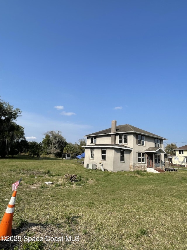 back of property with a yard and a chimney