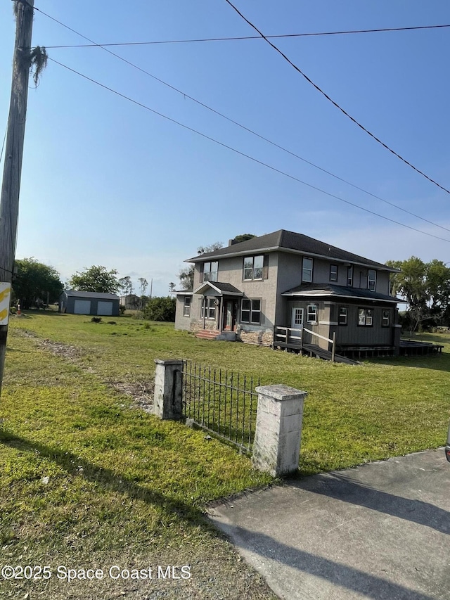 view of front facade featuring a front yard, fence, and an outdoor structure