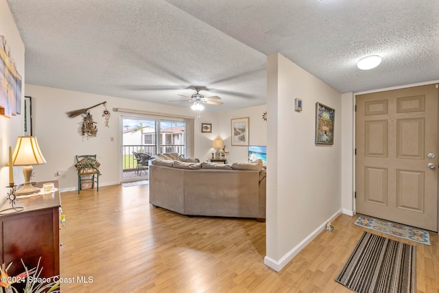 living room with ceiling fan, wood-type flooring, and a textured ceiling