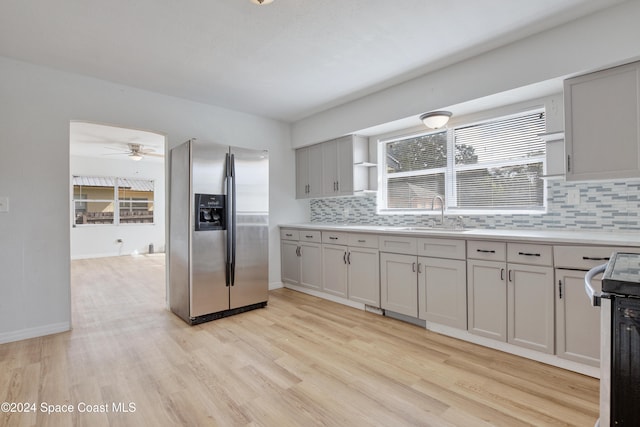 kitchen with stainless steel refrigerator with ice dispenser, range with electric cooktop, ceiling fan, sink, and light hardwood / wood-style flooring