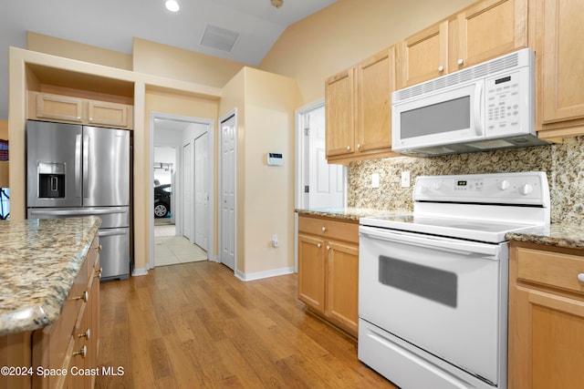 kitchen featuring white appliances, light stone countertops, light hardwood / wood-style floors, lofted ceiling, and decorative backsplash