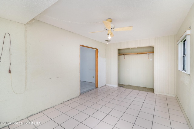 unfurnished bedroom with light tile patterned floors, ceiling fan, and a closet