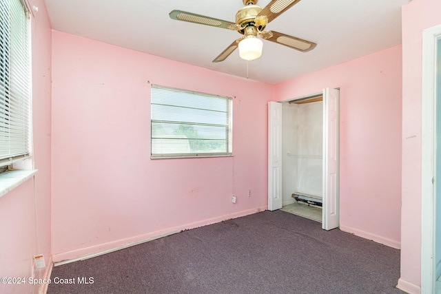 unfurnished bedroom featuring ceiling fan, dark colored carpet, and a closet