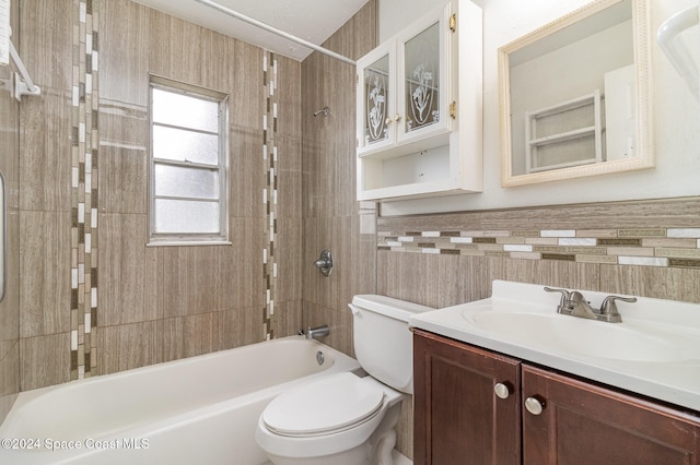 full bathroom featuring tile walls, vanity, tiled shower / bath combo, and toilet