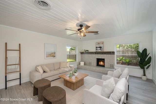 living room with a healthy amount of sunlight, ornamental molding, a fireplace, and light hardwood / wood-style flooring