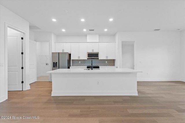 kitchen with light hardwood / wood-style flooring, white cabinets, an island with sink, and stainless steel appliances