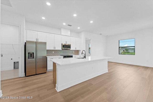 kitchen featuring appliances with stainless steel finishes, a sink, light wood-type flooring, white cabinetry, and recessed lighting