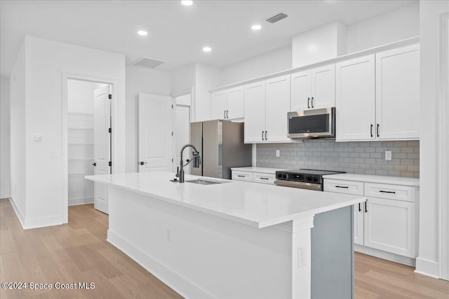 kitchen with a kitchen island with sink, light hardwood / wood-style floors, stainless steel appliances, and sink