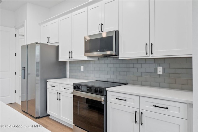kitchen with appliances with stainless steel finishes, light countertops, white cabinetry, and light wood-style flooring
