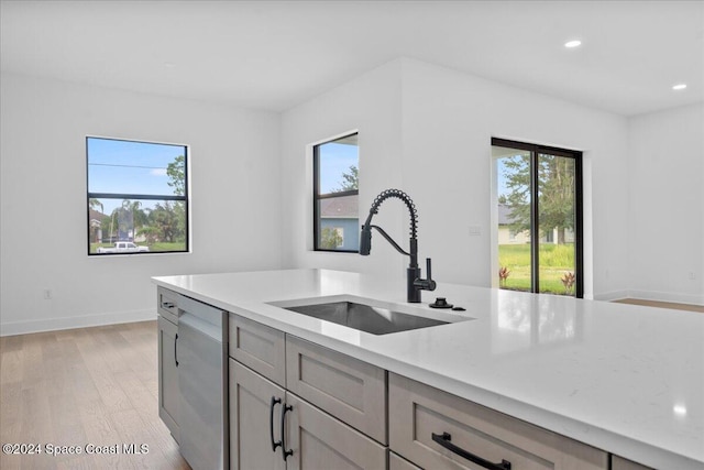 kitchen with a sink, dishwasher, gray cabinets, light wood finished floors, and recessed lighting