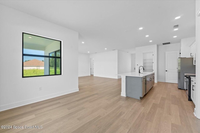 kitchen featuring stainless steel appliances, light countertops, light wood-type flooring, open floor plan, and recessed lighting