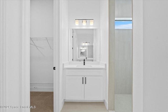 bathroom featuring a spacious closet, a walk in shower, and vanity