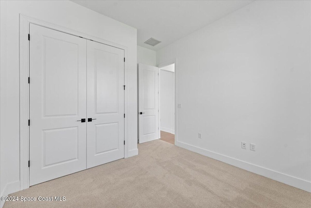 unfurnished bedroom featuring light colored carpet and a closet