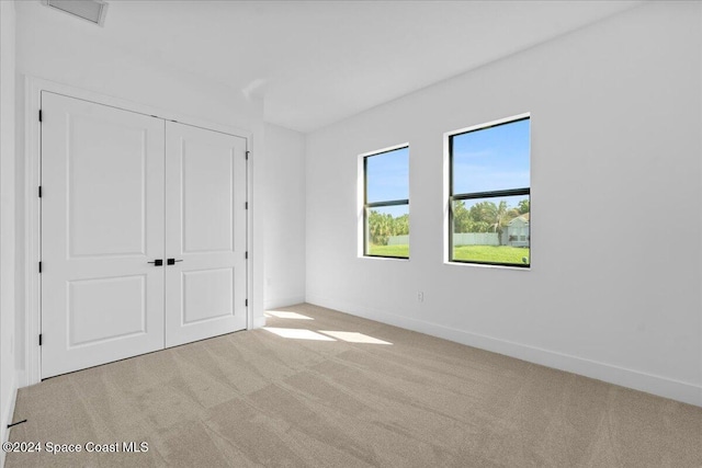 unfurnished bedroom featuring light carpet and a closet