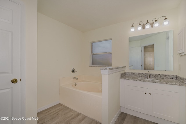 bathroom with wood-type flooring, a tub to relax in, and vanity