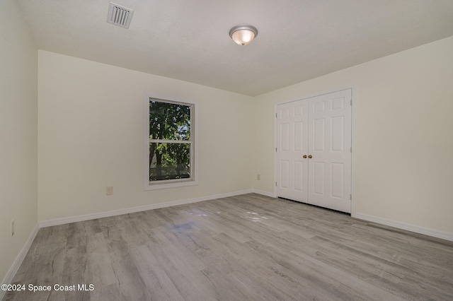 unfurnished bedroom featuring light wood-type flooring, a textured ceiling, and a closet