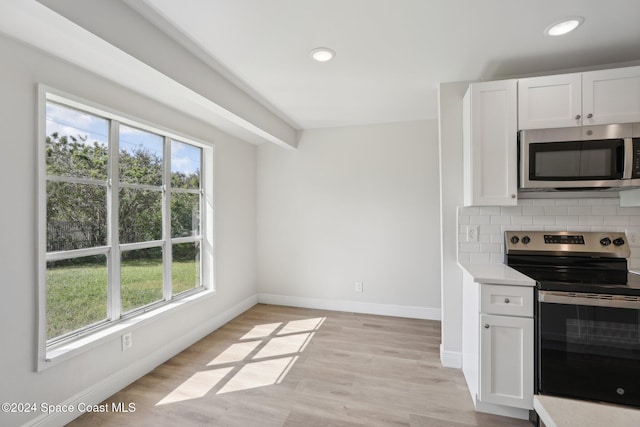 kitchen with backsplash, white cabinetry, light hardwood / wood-style flooring, and stainless steel appliances