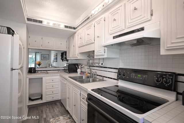 kitchen featuring white cabinets, white fridge, and black electric range