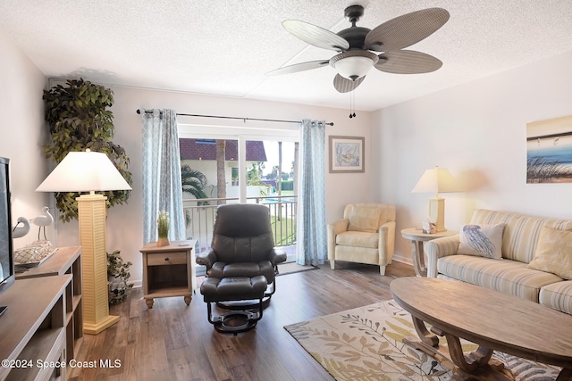 living room with ceiling fan, dark wood-type flooring, and a textured ceiling