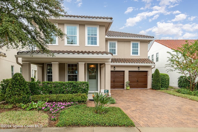 mediterranean / spanish-style home with a garage and a porch