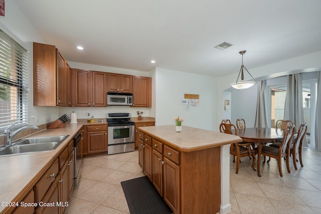 kitchen featuring a center island, sink, light tile patterned floors, appliances with stainless steel finishes, and decorative light fixtures